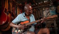 Guitar luthier Misoko Nzalayala Jean-Luther, alias Socklo, 61, plays one of the guitars he is repairing at his workshop in Kinshasa, Democratic Republic of Congo, October 18, 2021. REUTERS/Justin Makangara