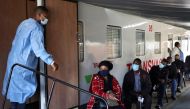 A health worker talks to people as they wait to register next to the Transvaco coronavirus disease (COVID-19) vaccine train, after South Africa's rail company Transnet turned the train into a COVID-19 vaccination center on rails to help the government speed up its vaccine rollout in the country's remote communities, at the Springs train station on the East Rand, South Africa, August 30, 2021. REUTERS/Siphiwe Sibeko/File Photo