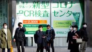 People wait to cross the street in front of a PCR testing centre, on the first day of Japan's closed borders to prevent the spread of the Omicron variant of coronavirus, in Tokyo, Japan November 30, 2021. REUTERS/Androniki Christodoulou