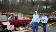 Bill Mosley walks with his wife Bonnie while carrying two of his guns, the only items he was able to recover after their home was destroyed, as a devastating outbreak of tornadoes ripped through several U.S. states in Earlington, Kentucky, U.S. December 11, 2021. REUTERS/Cheney Orr