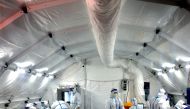 Medical workers in protective suits work inside a makeshift nucleic acid testing laboratory set up at a convention centre following the coronavirus disease (COVID-19) outbreak in Xian, Shaanxi province, China December 22, 2021. cnsphoto via Reuters