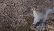 A Cal fire water dropping helicopter drops its payload on a hot spot as the Colorado fire burns near Big Sur, California, U.S. January 22, 2022. REUTERS/Peter DaSilva