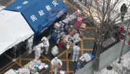 Workers in protective suits sort supplies to be delivered to residents at a compound under lockdown, in Fengtai district of Beijing, China January 23, 2022. cnsphoto via Reuters