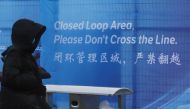 A pedestrian passes a sign marking the barrier of the 