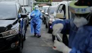 Medical workers prepare to take swab samples from people at a drive-thru coronavirus (COVID-19) test station, as the Omicron coronavirus variant spreads, in Jakarta, Indonesia, February 7, 2022. REUTERS/Willy Kurniawan