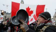 A person bangs pans as trucks honk their horns again, as truckers and supporters continue to protest coronavirus disease (COVID-19) vaccine mandates, in Ottawa, Ontario, Canada, February 11, 2022. Reuters/Lars Hagberg