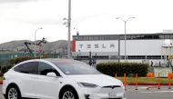 A Tesla vehicle drives past Tesla's primary vehicle factory after CEO Elon Musk announced he was defying local officials' coronavirus disease (COVID-19) restrictions by reopening the plant in Fremont, California, U.S. May 11, 2020. REUTERS/Stephen Lam/File Photo