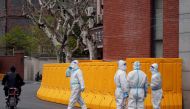 Workers in protective suits stand next to a sealed-off area before the second stage of a two-stage lockdown to curb the spread of the coronavirus disease (COVID-19), in Shanghai, China March 31, 2022. REUTERS/Aly Song