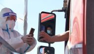A police officer in a protective suit checks the information of a truck driver at a toll gate of a highway following the coronavirus disease (COVID-19) outbreak, in Fuxin, Liaoning province, China April 15, 2022. cnsphoto via REUTERS