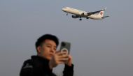 FILE PHOTO: A man takes a selfie as a plane of China Eastern Airlines lands at the Beijing Capital International Airport in Beijing, China March 23, 2022. REUTERS