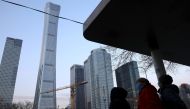 People wait at a bus stop in Beijing's Central Business District (CBD), China January 16, 2022. Picture taken January 16, 2022. REUTERS/Tingshu Wang/File Photo