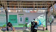 A man checks his mobile phone as he waits while recharging his Ola electric scooter at an electric vehicle charging station in New Delhi, India, February 12, 2022. REUTERS/Aditi Shah//File Photo