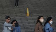 Women wearing protective masks to prevent contracting the coronavirus disease (COVID-19) walk past a couple who takes a selfie photo without masks in Seoul, South Korea, May 2, 2022. Reuters/Kim Hong-Ji
