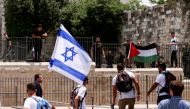 Israelis stand with an Israeli flag opposite to Palestinians with Palestinian flag next to Damascus gate to Jerusalem's Old City May 29, 2022. REUTERS/Ammar Awad