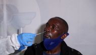 A healthcare worker collects a swab from a passenger for a PCR test against the coronavirus disease (COVID-19) before traveling to Uganda, amidst the spread of the new SARS-CoV-2 variant Omicron, at O.R. Tambo International Airport in Johannesburg, South Africa, November 28, 2021. REUTERS/ Sumaya Hisham/File Photo
