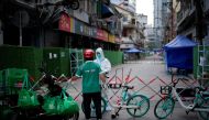 A worker in a protective suit gets food from a delivery worker at a closed residential area during lock-down, amid the coronavirus disease (COVID-19) outbreak, in Shanghai, China, on May 25, 2022. (REU-TERS/Aly Song/File Photo)