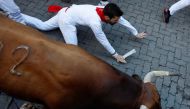 A reveller falls next to a bull during the running of the bulls at the San Fermin festival in Pamplona, Spain, July 11, 2022. (Reuters/Vincent West)