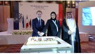 Minister of Social Development and the Family H E Mariam bint Ali bin Nasser Al Misnad and French Ambassador to Qatar H E Jean-Baptiste Faivre cutting the ceremonial cake, while  Director of Protocol at the Ministry of Foreign Affairs H E Ambassador Ibrahim Yousif Fakhroo looks on.