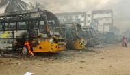 People walk past damaged school buses that were set on fire by a mob in the school campus after a female student's death in Kallakurichi district in the southern state of Tamil Nadu, India, July 17, 2022. (REUTERS)
