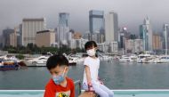 Children wearing face masks rest next to Victoria Harbour, amid the coronavirus disease (COVID-19) pandemic, in Hong Kong, China, March 25, 2022. REUTERS/Tyrone Siu/File Photo