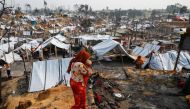 A Rohingya refugee woman carries her child after a massive fire broke out two days ago in Cox's Bazar, Bangladesh, March 24, 2021. REUTERS/Mohammad Ponir Hossain

