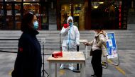 A worker in a protective suit guides people to scan QR health code before taking a test for the coronavirus disease (COVID-19) at a testing booth, in Beijing, China, on October 27, 2022. REUTERS/Tingshu Wang/File Photo