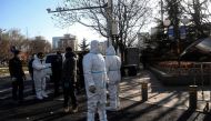 People wear personal protective equipment (PPE) along a street in Beijing on December 5, 2022. (Photo by Noel Celis / AFP)