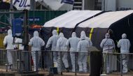 Forensics police officers arrive at the marina in Dover, southeast England, on December 14, 2022 to inspect the bodies of migrants believed to be kept inside a tent outside the UK Royal National Lifeboat Institution (RNLI) office after they died overnight while attempting to cross the English Channel. (Photo by CARLOS JASSO / AFP)