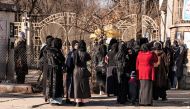 Afghan female university students stop by Taliban security personnel stand next to a university in Kabul on December 21, 2022. (Photo by Wakil Kohsar / AFP)