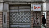 An Afghan man walks past the office of a foreign aid group 'Care' in downtown Kabul on December 26, 2022. (AFP)