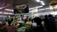 People wearing face masks following the coronavirus disease (COVID-19) outbreak shop for vegetables near an image of Beijing Communist Party Secretary Cai Qi at a market in Beijing, China January 15, 2021. Picture taken January 15, 2021. REUTERS/Tingshu Wang/File Photo
