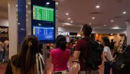 Passengers look at a screen showing flight information at terminal 3 of Ninoy International Airport in Pasay, Metro Manila on January 1, 2023. (Photo by KEVIN TRISTAN ESPIRITU / AFP)