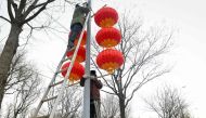Workers hang red lanterns on a light pole along a street for the upcoming Chinese Lunar New Year celebrations in Beijing on January 14, 2023. (Photo by WANG Zhao / AFP)