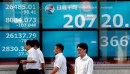 Men walk past in front of an electric screen showing Japan's Nikkei share average outside a brokerage in Tokyo, Japan, August 5, 2019. File Photo: REUTERS/Issei Kato
