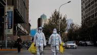 Pandemic prevention workers in protective suits cross a street as coronavirus disease (COVID-19) outbreaks continue in Beijing, December 9, 2022. (REUTERS/Thomas Peter)