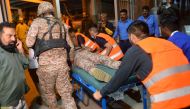 Volunteers carry an injured paramilitary soldier to a hospital following an attack on a police compound in Karachi on February 17, 2023. (Photo by Rizwan Tabassum / AFP)