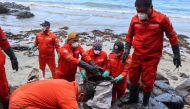 This handout photo taken on March 8, 2023 and released by the Philippine Coast Guard (PCG) shows coast guard personnel and volunteers collecting debris covered with oil during a clean-up along the coast in Pola, Oriental Mindoro Province, days after an oil spill from a sunken tanker. (Photo by Handout / Philippine Coast Guard (PCG) / AFP)