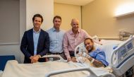This handout picture provided by Aspetar Hospital in Doha on March 10, 2023 shows Paris Saint-Germain's Brazilian forward Neymar da Silva Santos Junior (R) gesturing in bed after after undergoing surgery at the facility, accompanied by the hospital's Chief Medical Officer Dr Pieter D'Hooghe (2nd-L), ankle surgeon Dr Pierre James Calder (2nd-R), and Brazilian surgeon and national team doctor Rodrigo Lasmar (L). (Photo by Aspetar Hospital Doha / AFP)