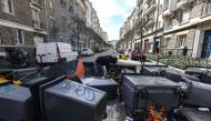 A protestor stands among rubbish bins with burning materiel during a demonstration on the eighth day of strikes and protests across the country against the government's proposed pensions overhaul, in Rennes, western France on March 15, 2023. (Photo by Jean-Francois Monier / AFP)