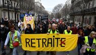 Protesters participate in a march holding a banner which reads as 