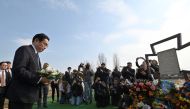 Japan's Prime Minister Fumio Kishida pays his respect at the site of a mass grave found on the grounds of the church of Saint Andrew Pervozvannoho All Saints in the town of Bucha, during a visit to Ukraine on March 21, 2023. (Photo by Sergei Chuzavkov / AFP)