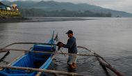 In this picture taken on March 22, 2023, a fisherman prepares his boat to transport passengers in Pola, Oriental Mindoro province, one of the areas affected by an oil spill from the sunken tanker Princess Empress. Photo by JAM STA ROSA / AFP