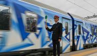 A station master holds a signalling disc as the first train since a deadly train disaster leaves from Athens' main station to Thessaloniki on April 3, 2023. Photo by Louisa GOULIAMAKI / AFP