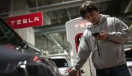 This photo taken on January 27, 2023 shows Atsushi Ikeda, the founder and vice president of a Japanese club for Tesla owners, checking his phone as he charges his Tesla Model S at a charging station in Tokyo. Photo by Yuichi YAMAZAKI / AFP