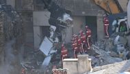 Firefighters stand aside as an excavator clears rubble at 'rue Tivoli' after a building collapsed in the street, in Marseille, southern France, on April 9, 2023. Photo by CLEMENT MAHOUDEAU / AFP