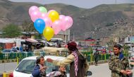 An Afghan boy selling balloons talks to a Taliban security personnel along a street in Fayzabad district of Badakhshan province on April 10, 2023. (Photo by OMER ABRAR / AFP)