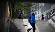 A man carrying bags of vegetables walk through an underpass in Beijing on April 11, 2023. (Photo by WANG Zhao / AFP)