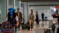 Passengers walk through the arrivals hall for international flights at the Capital International Airport in Beijing on March 14, 2023. Photo by Jade GAO / AFP

