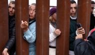 Immigrants seeking asylum in the US, who are stuck in a makeshift camp between border walls between the US and Mexico, reach through the border wall as volunteers offer assistance on the other side on May 12, 2023 in San Diego, California. Mario Tama/Getty Images/AFP 