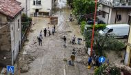 An aerial view taken on May 18, 2023 shows residents clearing mud in a street of Cesena after heavy rains caused flooding across Italy's northern Emilia Romagna region, killing five people. Photo by Alessandro SERRANO / AFP